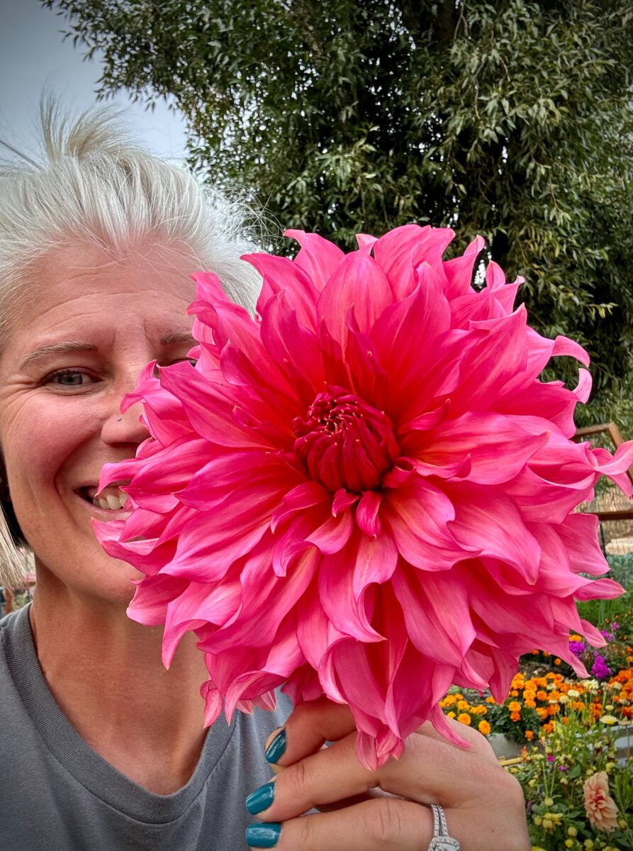 Angela holding a vivid pink dahlia at Flower Girl Farm