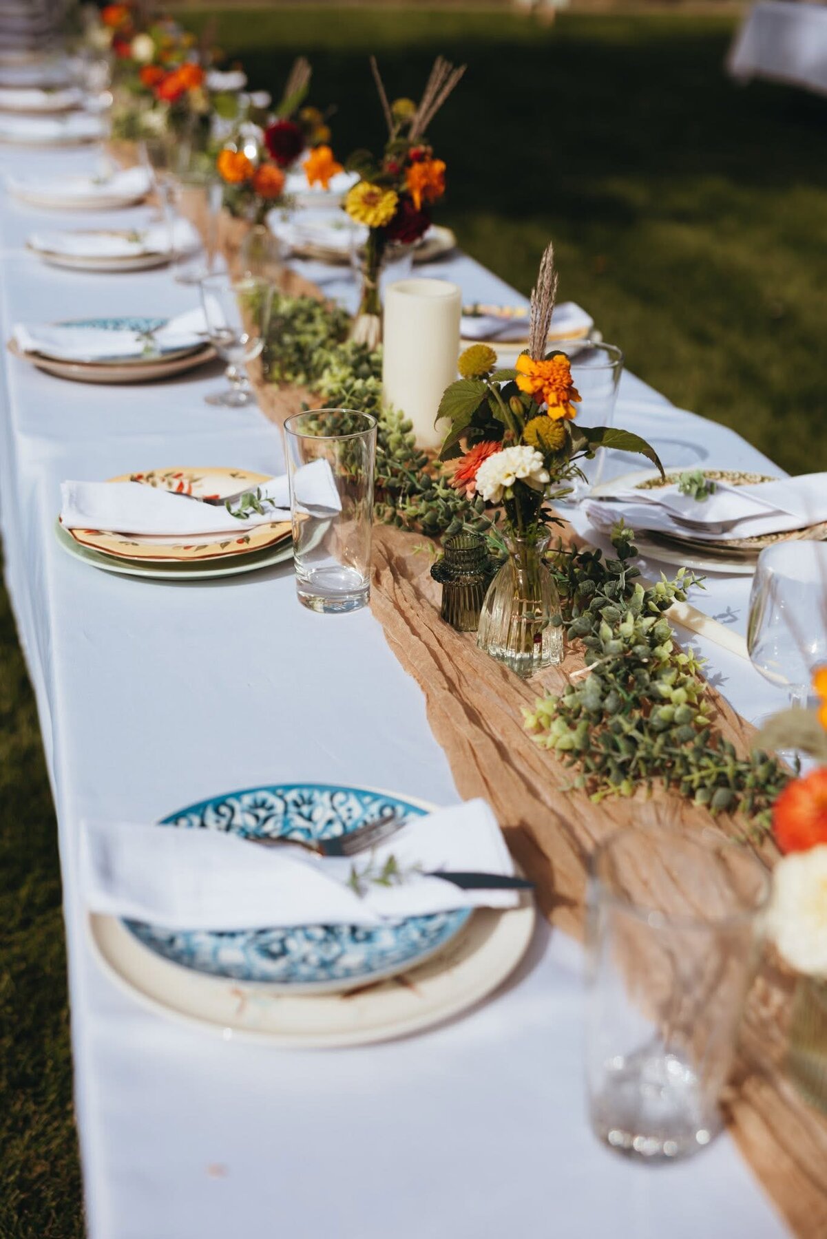 Outdoor wedding table decorated with colorful bud vases and greenery